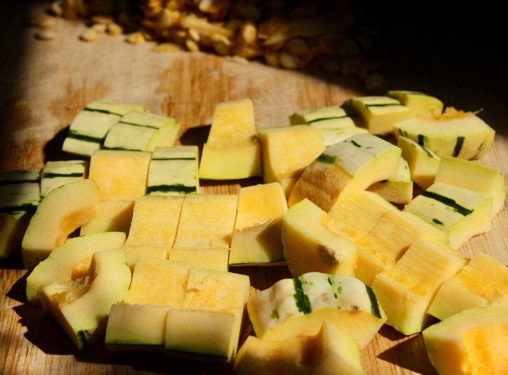 Chopped pieces of yellow squash and zucchini on a wooden cutting board.